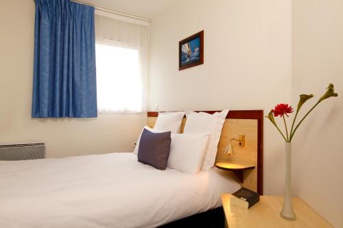 克莱蒙费朗Appart'City Classic Clermont Ferrand Centre的配有一张床和花瓶的酒店客房