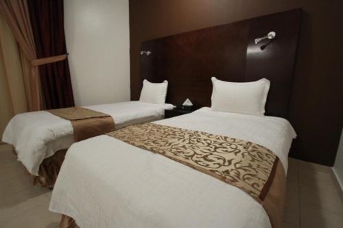 迈季迈阿Raoum Inn Majmaa的酒店客房,配有两张带白色床单的床