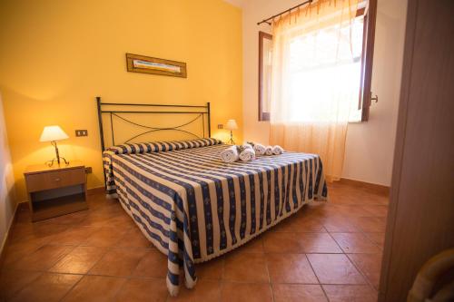 斯克佩罗Villa Chiara的一间卧室配有一张带条纹毯子的床和窗户