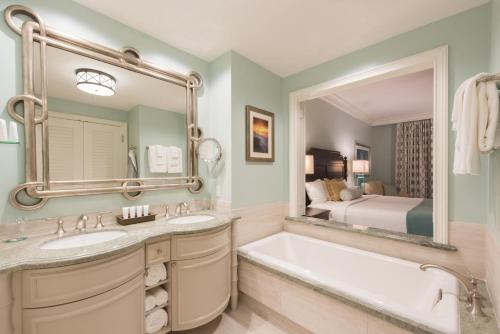 德斯坦Henderson Beach Resort的一间带两个盥洗盆、一个浴缸和一张床的浴室