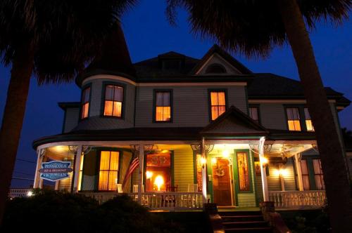 彭萨科拉Pensacola Victorian Bed & Breakfast的夜晚门廊上悬挂美国国旗的房子