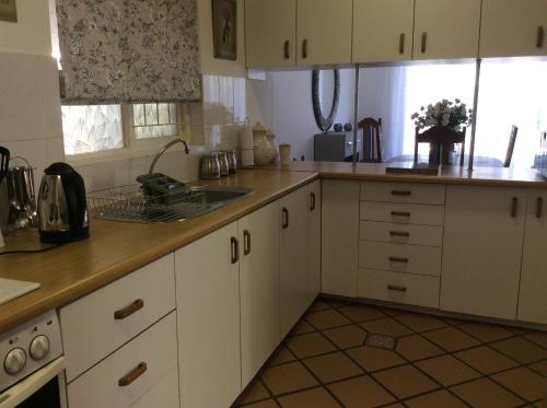开普敦On Broadwalk Cottage的厨房配有白色橱柜和水槽