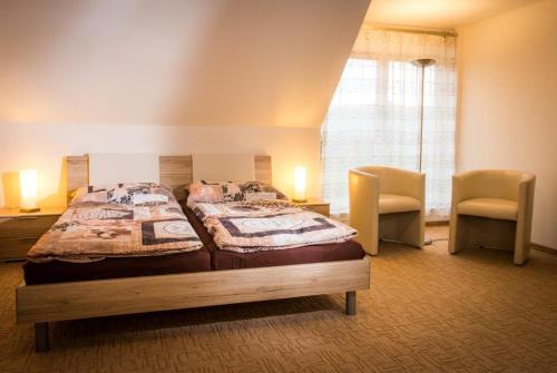 新博尔Golf Resort Česká Lípa的一间卧室配有一张大床和两把椅子