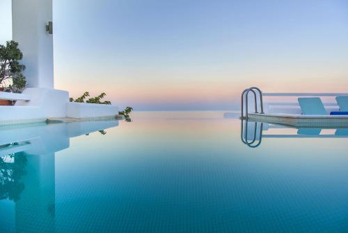 VourvoúlosAnema Boutique Hotel & Villas Santorini的水中带两把椅子的游泳池
