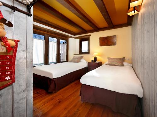 维耶拉Apartamento Amets de Aran的客房内设有两张床,配有木地板和窗户。