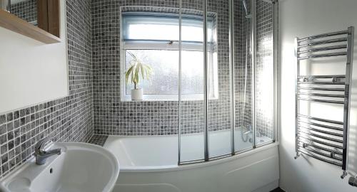 雷利Castle Cottage的带浴缸、水槽和窗户的浴室