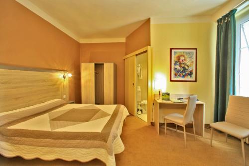 绍维尼Logis Hôtel Le Lion d'Or的配有一张床和一张书桌的酒店客房