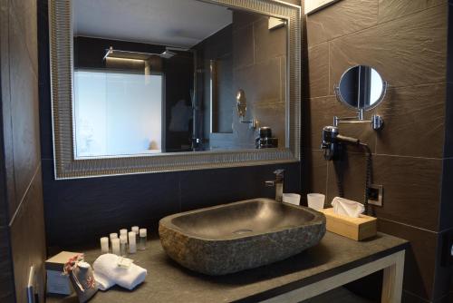 韦松纳Hôtel Chalet Royal的一间带大型石质水槽和镜子的浴室