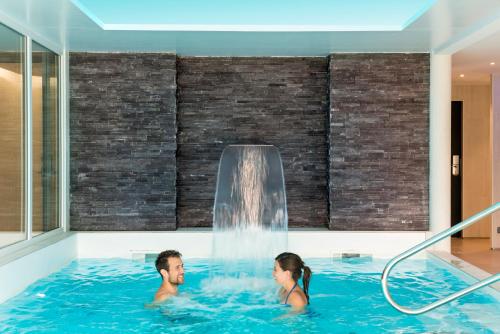 布吕兹Domaine de Cicé-Blossac, Resort Spa & Golf的男人和女人在带瀑布的热水浴缸中