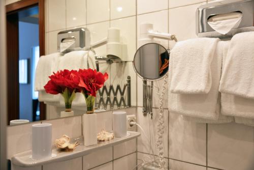 慕尼黑意大利酒店的浴室设有镜子和红色的花朵,位于柜台上