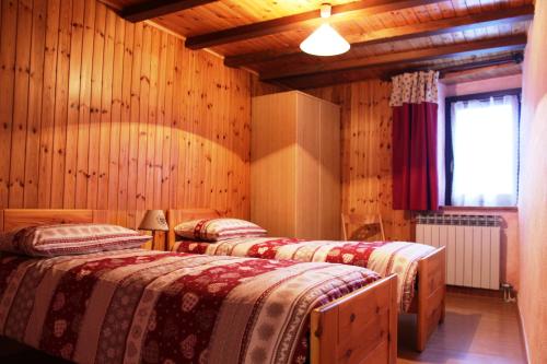 布吕松Maison Leveque的配有木墙和窗户的三张床