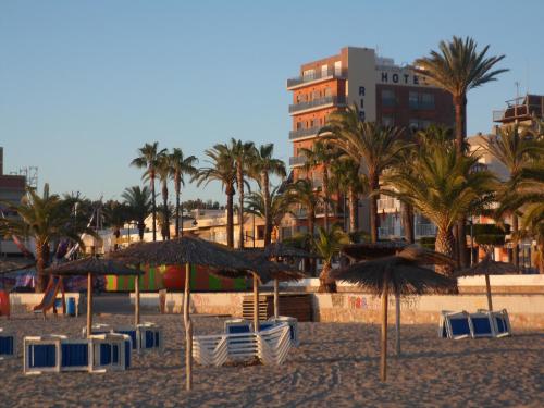 圣地亚哥德拉里贝拉Hotel Ribera的海滩上设有椅子和遮阳伞,棕榈树
