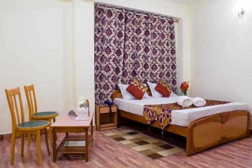 甘托克Hotel Renam的酒店客房带一张床、一张桌子和椅子