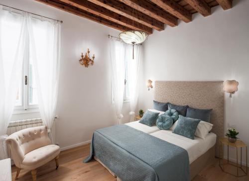 威尼斯Ca del Mar Venice Luxury Apartments的一间卧室配有一张大床和一把椅子