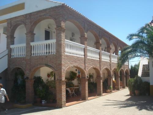 博罗尼亚Apartamentos Bolonia Paraiso的一座带拱门和棕榈树的大型砖砌建筑