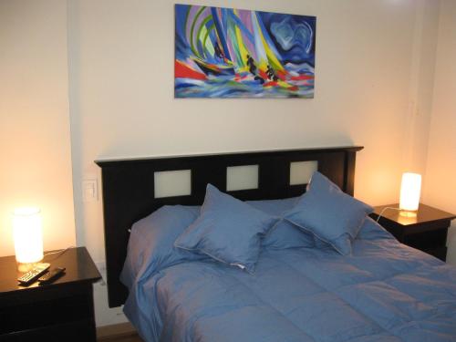 布兰卡港Bahiaxdia Paraguay的一间卧室配有一张带蓝色枕头的床和一幅画