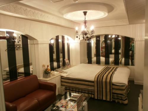 名古屋派亚特酒店（仅限成人）的一间卧室配有一张床、一张沙发和一个吊灯。