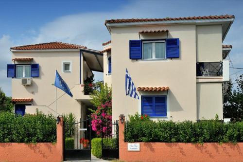 利吉亚Anesis Village Studios and Apartments的前面有蓝色百叶窗和旗帜的建筑