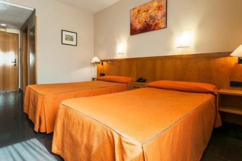 维多利亚-加斯特伊兹鲁塔欧罗巴酒店的配有橙色床单的酒店客房内的两张床