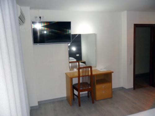 萨拉戈萨Hotel Delicias的一间房间,配有一张桌子和一台墙上的电视