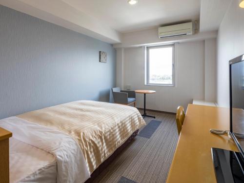 东近江市八日市康福特茵酒店的酒店客房配有一张床、一张书桌和一台电视。