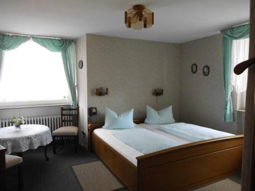 埃施韦格Hotel Garni am Heuberg的一间卧室配有一张床、一张桌子和一个窗户。