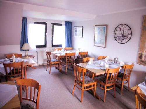 埃森花卉酒店的餐厅设有桌椅和墙上的时钟