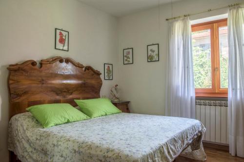 特雷维尼亚诺罗马诺Gli Ulivi的一间卧室配有一张带绿色枕头的床和一扇窗户