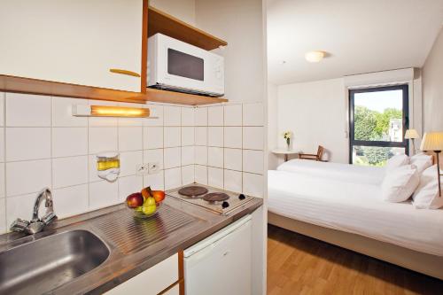 奥尔良奥尔良贞德公园&套房酒店的一个带水槽的厨房和一张位于客房内的床