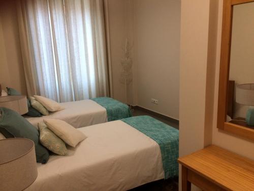 丰沙尔Apartamentos Sousa的酒店客房,设有两张床和镜子