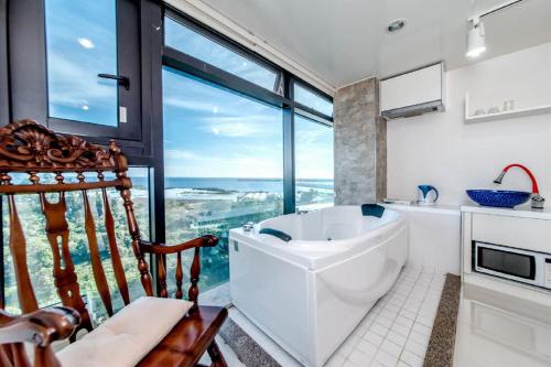 西归浦市奥利欧度假酒店的带浴缸的浴室和大窗户