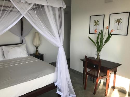 乌纳瓦图纳劳拉之家酒店的一间卧室配有一张天蓬床和一张桌子及椅子