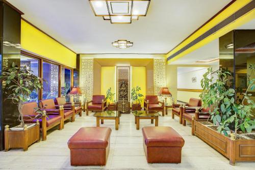 德拉敦Hotel Ajanta Continental的一间设有桌椅和植物的等候室