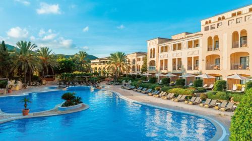 坎普德玛Steigenberger Hotel and Resort Camp de Mar的一个带椅子和棕榈树的度假游泳池