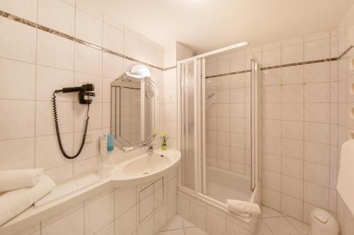 上阿斯巴赫蒙达纳酒店的带淋浴和盥洗盆的白色浴室