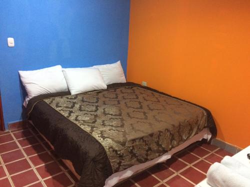 拉利伯塔德Coco Blue Resort的蓝色和橙色墙壁间的一张床位