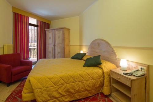 阿拉巴Hotel Portavescovo的一间卧室配有一张大床和一张红色椅子