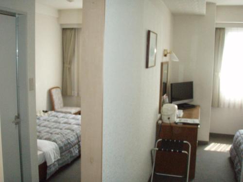 四万十市四万十新皇家酒店的酒店客房配有一张床、一张书桌和一台电视。