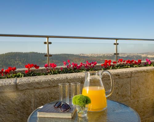 耶路撒冷Ein Kerem Hotel的一杯橙汁,坐在桌子上,放上一杯玻璃杯