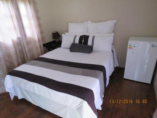 波罗瓜尼Klein Paradys Lodge - Polokwane的卧室配有一张白色大床,上面装有袋子