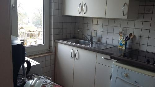 Comblain-au-PontGite Du bac的厨房配有白色橱柜、水槽和窗户。