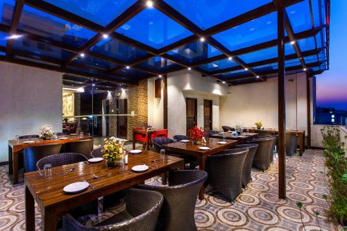 新德里日星赫瑞塔吉酒店的一间设有木桌和椅子的餐厅,享有美景