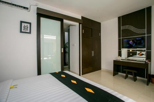 库塔戴安娜酒店的一间卧室配有一张床、一张书桌和一台电视。