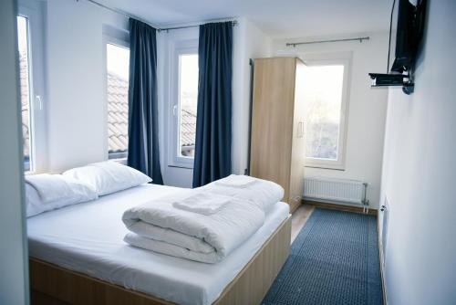 巴尼亚卢卡Motel Alibi的一间卧室配有一张带白色床单的床和两个窗户。