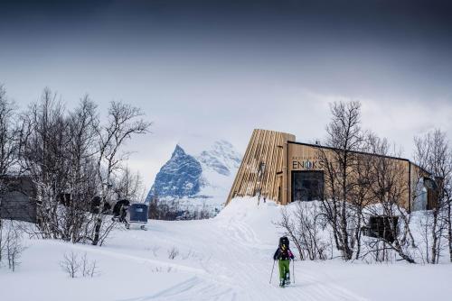 Nikkaluokta伊诺克斯拉迪加夫瑞山林小屋的滑雪者在建筑物前的雪中