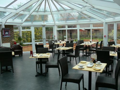 费勒姆旅程法尔汉姆索伦特度假酒店的餐厅设有桌椅和玻璃天花板。