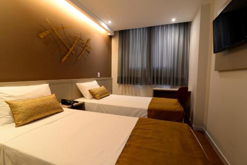 伊塔佩米林河畔卡舒埃鲁Easy Hotel Cachoeiro de Itapemirim by Atlantica的酒店客房设有两张床和一台平面电视。