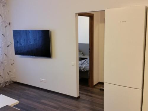 奥泰佩Tehvandi Ski Apartment的客房设有带电视和冰箱的白色墙壁。
