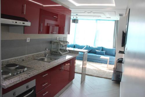 阿尤恩Résidence La Place的厨房配有红色橱柜和蓝色沙发