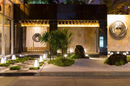 曼谷Bandara Suites Silom, Bangkok的一座建筑,前方有种有植物的庭院